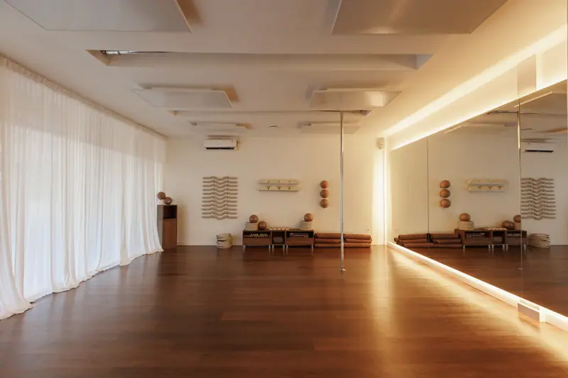 The empty SAWA Studio practice room, with infrared ceiling panels, a mirrored wall and warm wooden floors.